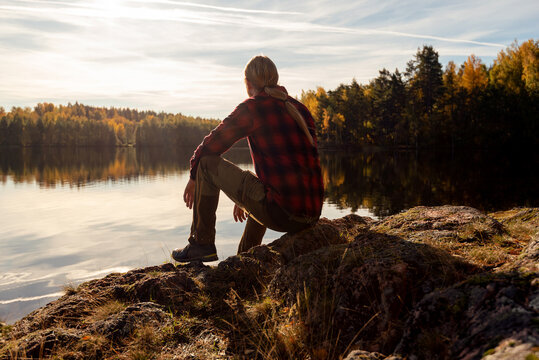 Male hiker sitting on the shore of a forest lake looking at the view and taking time for himself 