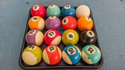 A collection of 15 billiard balls arranged in an irregular order. Including white balls. The ball is on the pool table. There are defects around the ball due to play.