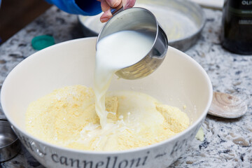 Baking bread at home by pouring milk into flour mixture