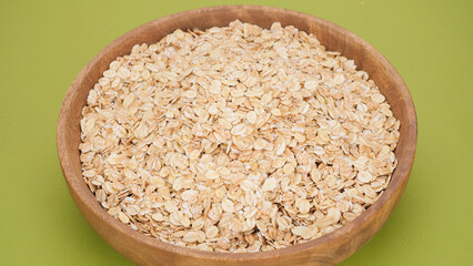 oatmeal in wooden bowl, green background. Healthy breakfast concept