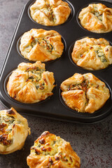 Spinach and feta muffins in puff pastry closeup in the maffin baking form on the table. Vertical