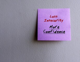 Purple sticky note on copy space grey wall written LESS INSECURITY, MORE CONFIDENCE concept of stop...