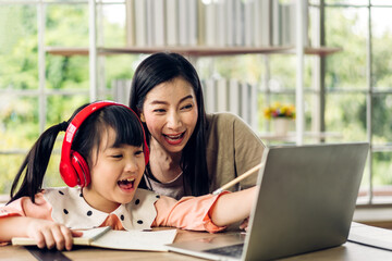 Mother and asian kid little girl learn and look at laptop computer reviewing lesson study with online education e-learning.student look for educational knowledge in homeschool at home.Education