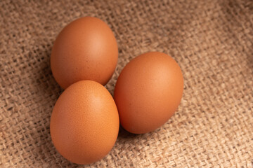 Three fresh chicken eggs on brown background