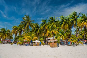 Fototapeta premium Cocos beach bar on a beach with white sand and palms on a sunny day, Isla Mujeres island, Caribbean Sea, Cancun, Yucatan, Mexico