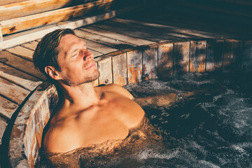 Man relaxing in wooden hot tub outdoor.  - obrazy, fototapety, plakaty