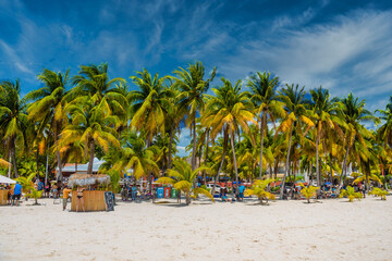 Fototapeta premium Cocos beach bar on a beach with white sand and palms on a sunny day, Isla Mujeres island, Caribbean Sea, Cancun, Yucatan, Mexico