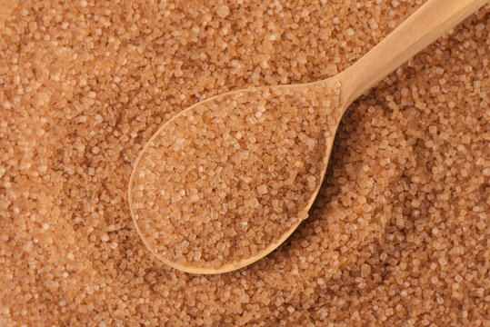 Top view of wooden spoon on brown cane sugar