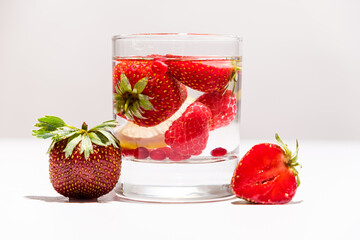 Summer cocktail with strawberries, raspberries and ice on a white background, side view.