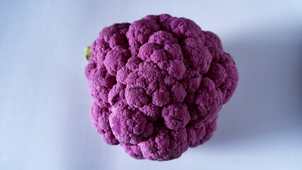 Whole violet or purple cauliflower on the white floor, isolated, top view.