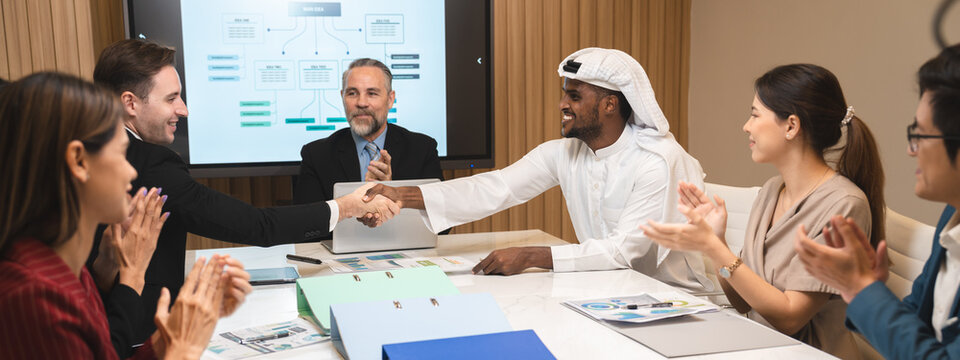Emirate man person having business deal agreements with partnership team, Arabian manager making handshake with businessman corporate group on table at office room, talk with Arab company from Dubai