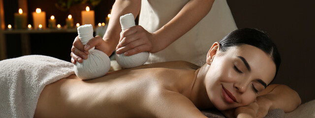 Young woman receiving herbal bag massage in spa salon. Banner design