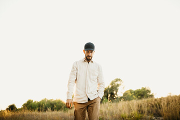 Portrait of a young bearded man wearing a black cap, at countryside