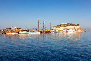 Boats at Marina with Castle on the Coast in a Touristic Town by the Aegean Sea. Kusadasi, Turkey. Sunny Morning Sunrise.