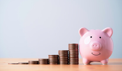 Pink piggy bank with increasing coins stacking on table , Money saving and deposit for investment...