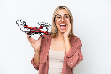 Woman holding a drone over isolated background shouting with mouth wide open