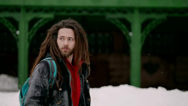 portrait of a young handsome and stylish man with dreadlocks and a beard, he walks around the city in winter