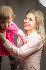A beautiful young mother with a little daughter is photographed in a home studio.