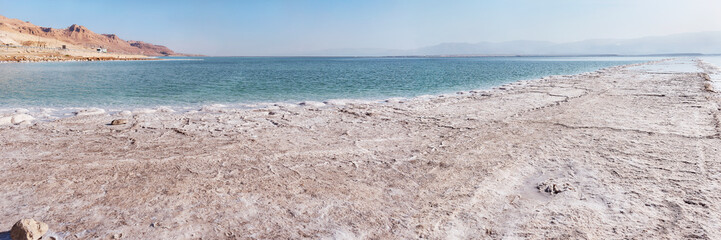 Obraz premium wide panorama that shows large flat industrial salt formations with the Dead Sea and barren desert hills in the background