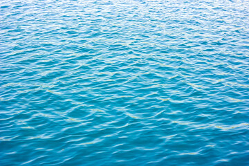 Light blue and turquoise sea water surface with waves texture in summer.