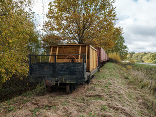Old narrow track production train resting on the rails in autumn countryside
