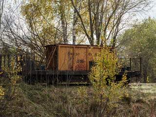 Old narrow track production train resting on the rails in autumn countryside