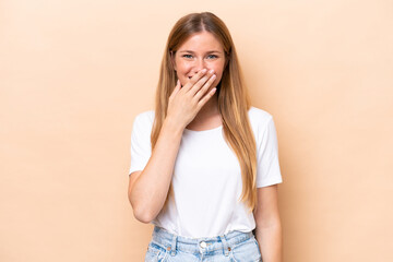 Young caucasian woman isolated on beige background happy and smiling covering mouth with hand