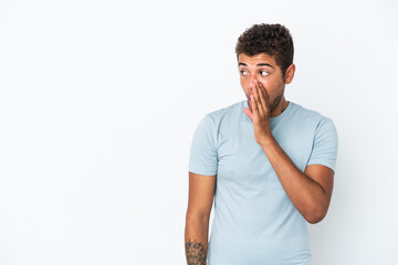 Young handsome Brazilian man isolated on white background whispering something with surprise gesture while looking to the side