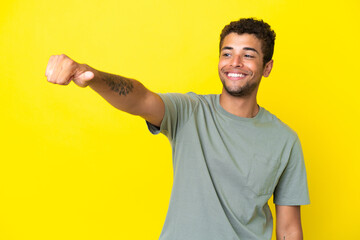 Young handsome Brazilian man isolated on yellow background giving a thumbs up gesture