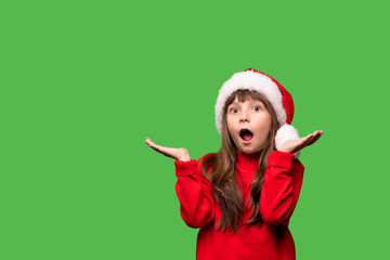 The girl in Santa's hat opened her mouth in surprise and her hands in different directions. Wow, what discounts, promotions and gifts on New Year's Eve and Christmas. Emotional portrait of a child.