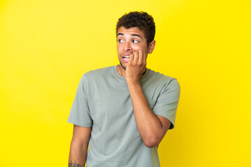 Young handsome Brazilian man isolated on yellow background is a little bit nervous