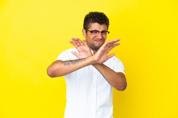 Young handsome Brazilian man isolated on yellow background nervous stretching hands to the front