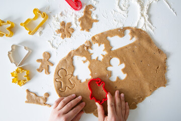 Female hands cutting gingerbread cookies for Christmas. Bakery preparation, top view. 
