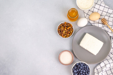 Cottage cheese, eggs, sugar, flour for making cheesecakes on a light background with space for text.