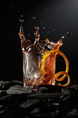 Piece of ice falls into the glass with a cocktail.