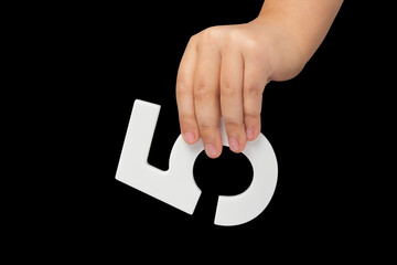 Number five in hand isolated on black background. Number five in the hand of a child holding on a...