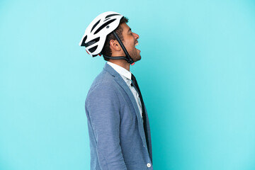 Young business Brazilian man with bike helmet isolated on blue background laughing in lateral position
