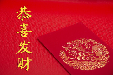 Chinese character - Gong Xi Fa Cai text with gold ingot and red packet on red background. Chinese...