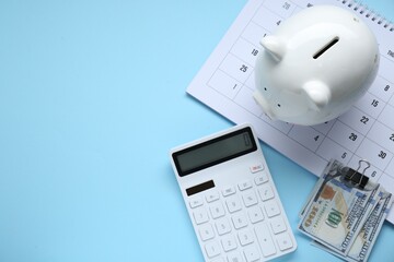 Flat lay composition with piggy bank and calculator on light blue background. Space for text