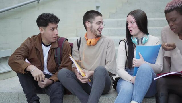 multi-ethnic group of students, take a break sitting on the stairs of the university campus.