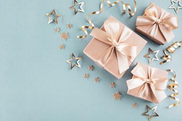 Gift boxes, golden stars and ribbons on blue turquoise background. Greeting card for Christmas, New Year and birthday.