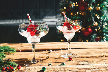 Christmas refreshment drink mimosa, punch or cranberry margarita cocktail serving in christmas ornaments and martini drinking glasses. Delicious icy drink idea for christmas and winter holiday party.