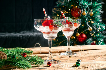 Christmas refreshment drink mimosa, punch or cranberry margarita cocktail serving in christmas ornaments and martini drinking glasses. Delicious icy drink idea for christmas and winter holiday party.
