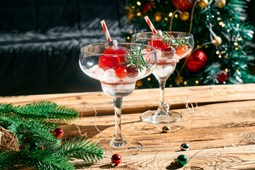 Christmas refreshment drink mimosa, punch or cranberry margarita cocktail serving in christmas ornaments and martini drinking glasses. Delicious icy drink idea for christmas and winter holiday party.