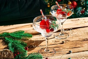 Christmas refreshment drink mimosa, punch or cranberry margarita cocktail serving in christmas ornaments and martini drinking glasses. Delicious icy drink idea for christmas and winter holiday party.