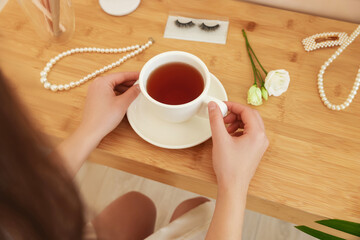 Bride with cup of tea at dressing table indoors, closeup. Wedding day