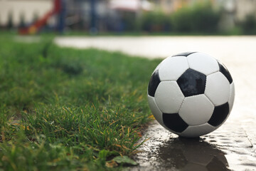 Fototapeta na wymiar Wet leather soccer ball on street, space for text