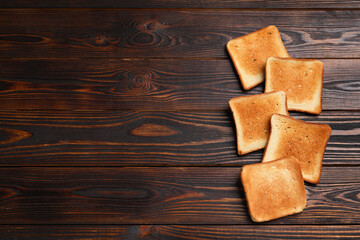 Slices of tasty toasted bread on wooden table, flat lay. Space for text