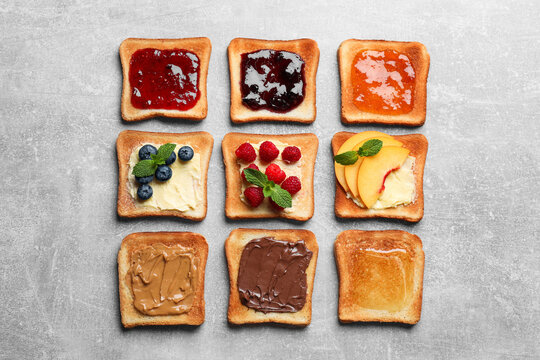 Tasty toasts with different spreads and fruits on light grey table, flat lay