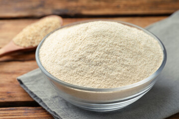 Glass bowl with quinoa flour on wooden table, closeup